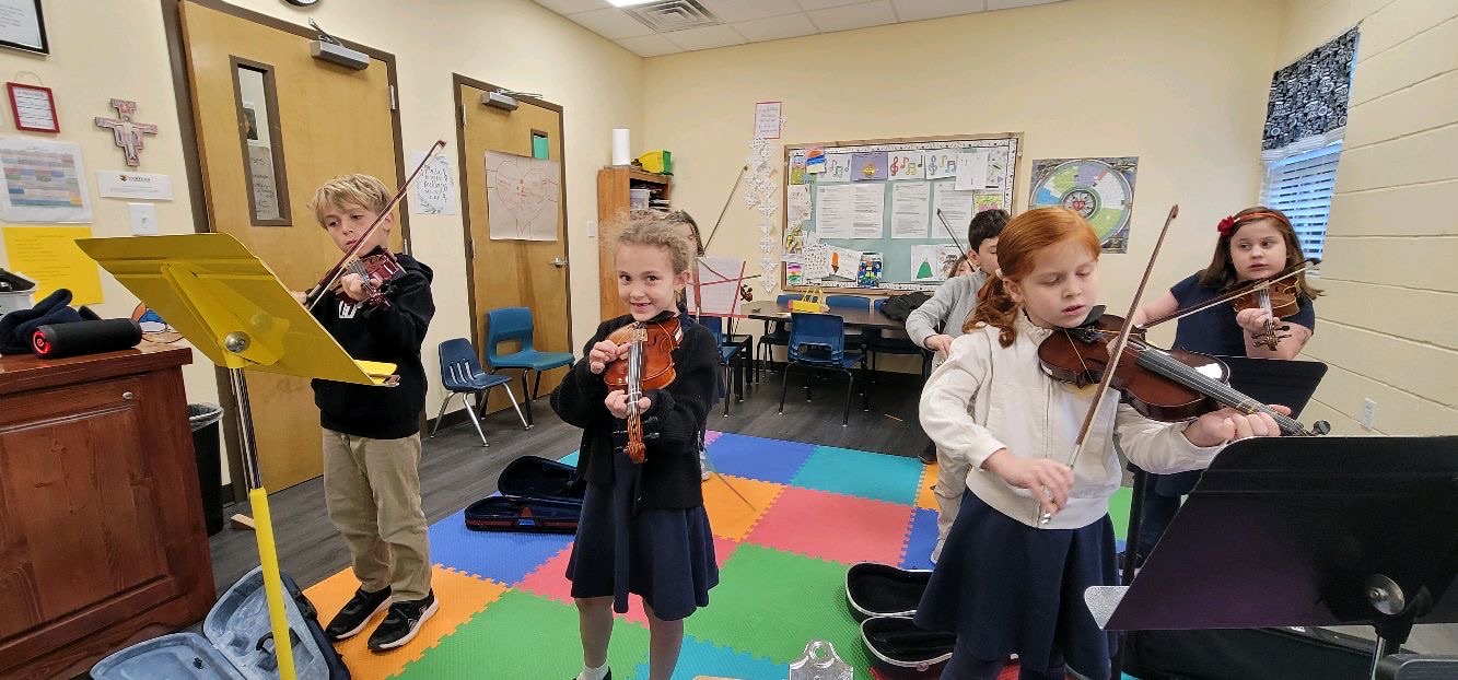Veritas students learning violin together in the classroom