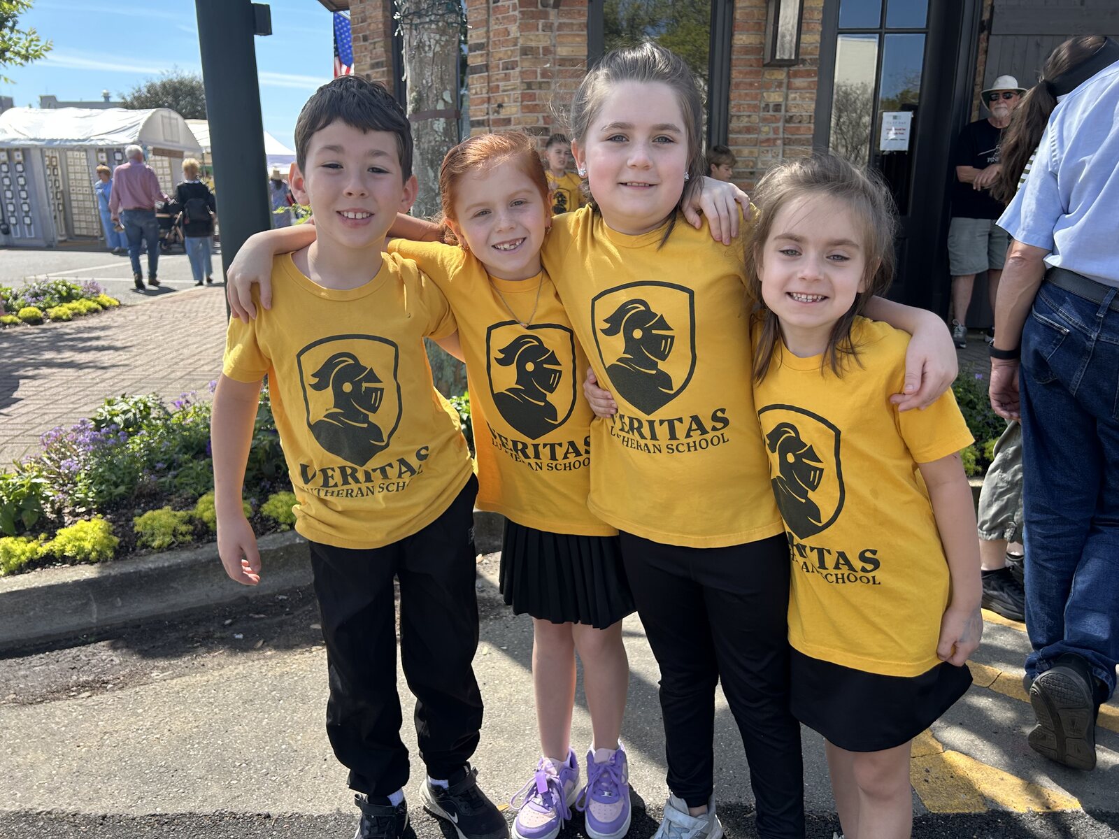Four Veritas students smiling together at a Fairhope community event